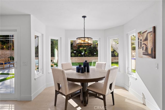 dining area with baseboards, a notable chandelier, and light wood finished floors