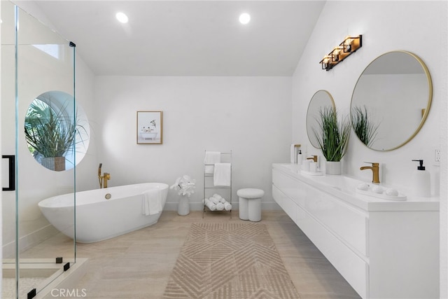 full bathroom with a sink, double vanity, plenty of natural light, and a freestanding bath