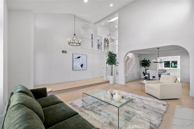 living area with visible vents, stairs, recessed lighting, arched walkways, and a notable chandelier