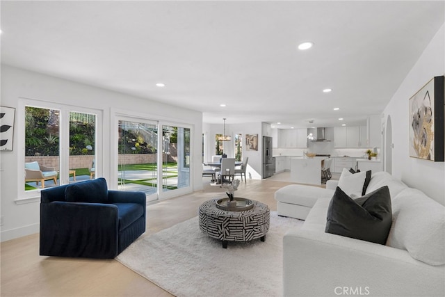 living room featuring recessed lighting, baseboards, and light wood-type flooring