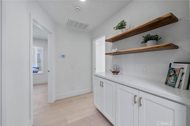 corridor featuring visible vents, baseboards, and light wood-style floors