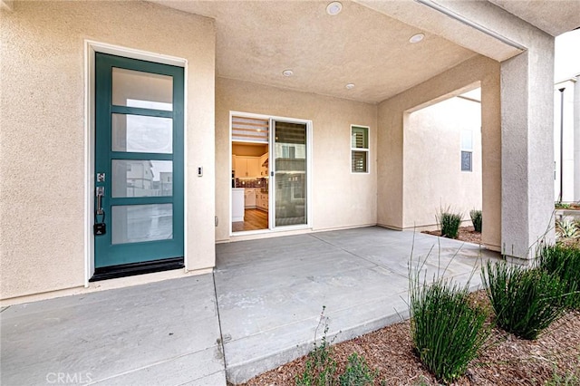 view of exterior entry with a patio area and stucco siding