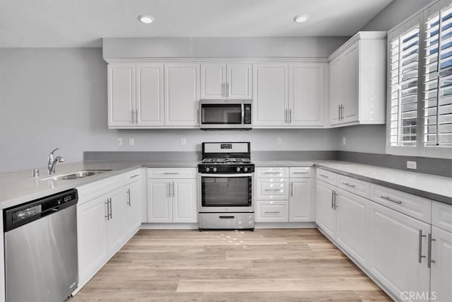 kitchen with recessed lighting, appliances with stainless steel finishes, light wood-style floors, white cabinets, and a sink