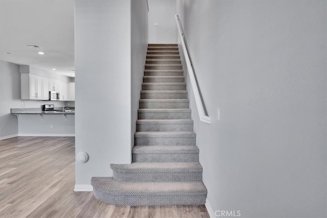 staircase with visible vents, recessed lighting, baseboards, and wood finished floors