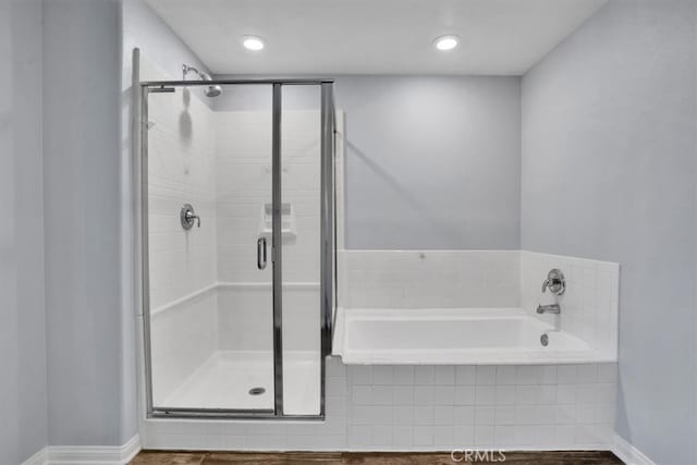 bathroom with a bath, recessed lighting, a shower stall, and baseboards