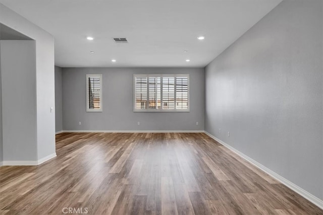 empty room featuring wood finished floors, visible vents, and baseboards