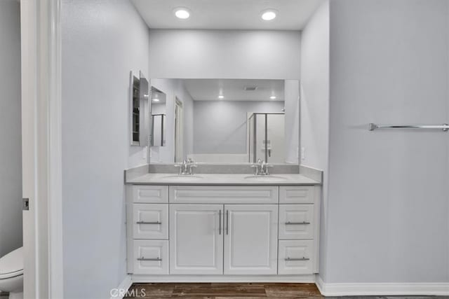 bathroom with a sink, toilet, double vanity, and a shower stall