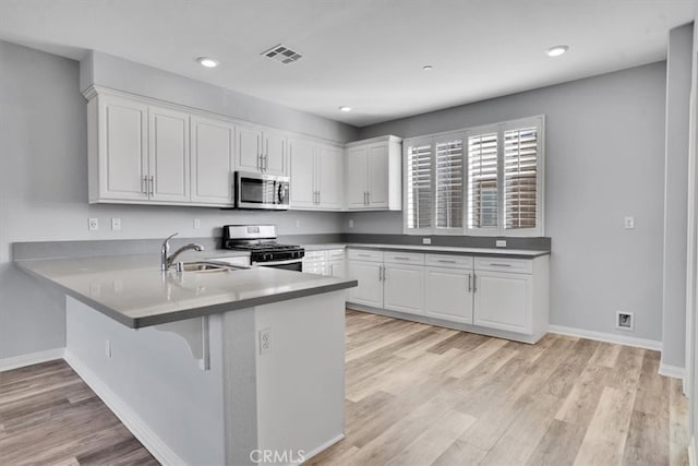 kitchen with light wood-type flooring, visible vents, a sink, stainless steel appliances, and white cabinets