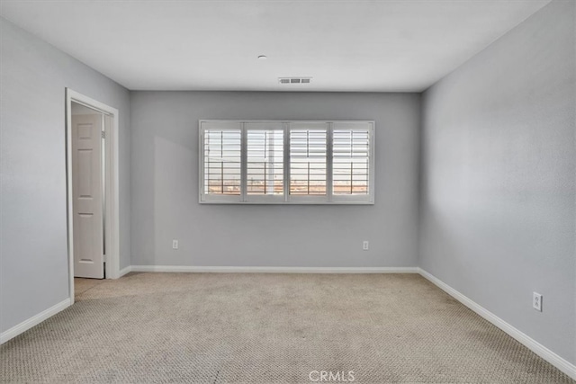 carpeted spare room with visible vents and baseboards