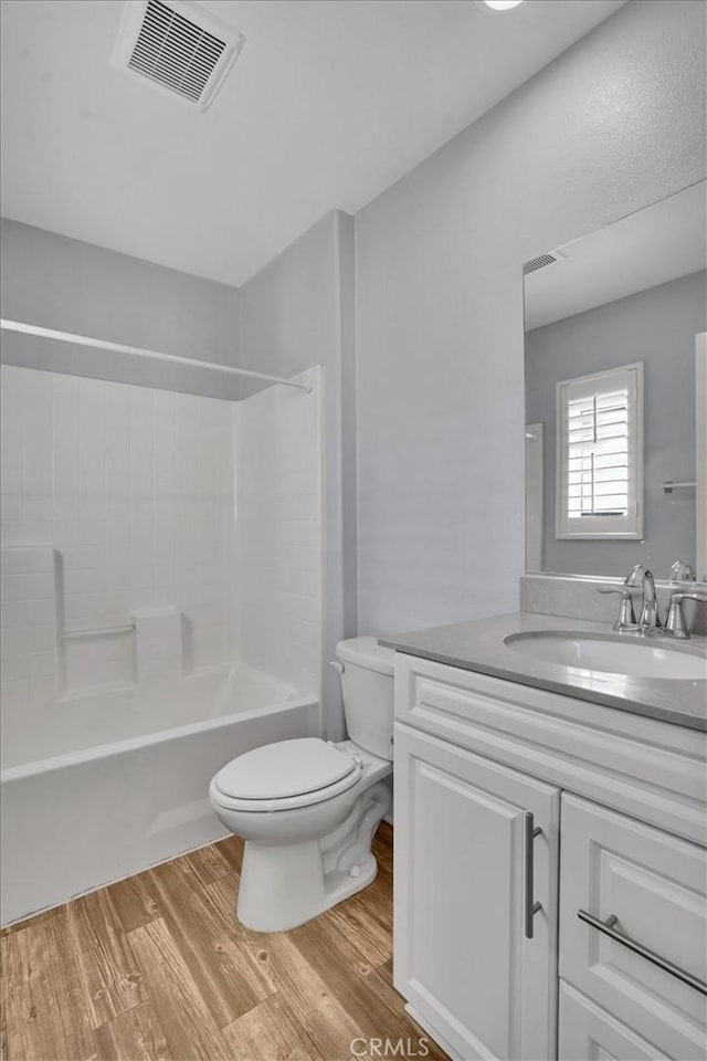 full bath with vanity, wood finished floors, visible vents, shower / bath combination, and toilet