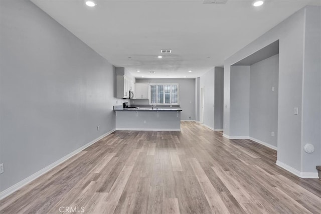 unfurnished living room with recessed lighting, light wood-style flooring, and baseboards