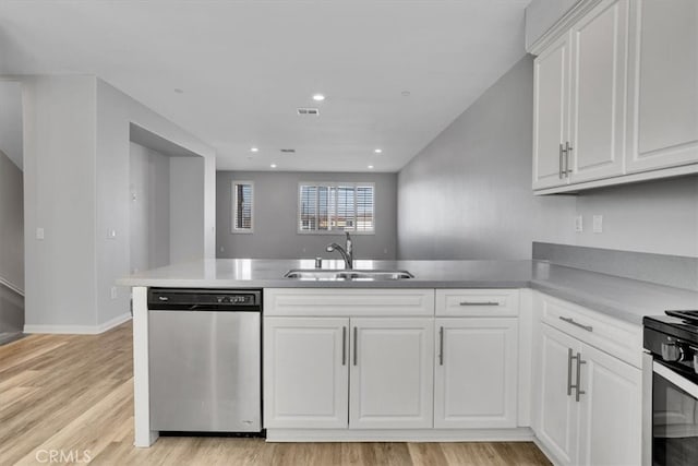 kitchen with light wood-type flooring, a sink, stainless steel appliances, a peninsula, and white cabinets