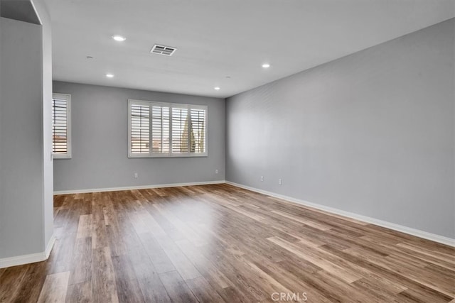 empty room with recessed lighting, visible vents, baseboards, and wood finished floors