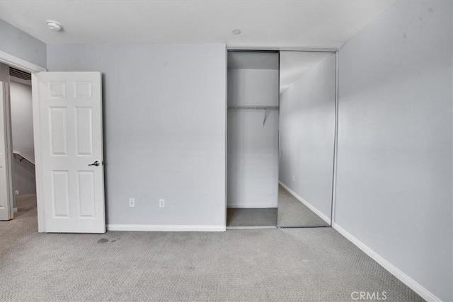 unfurnished bedroom featuring carpet flooring, baseboards, and a closet