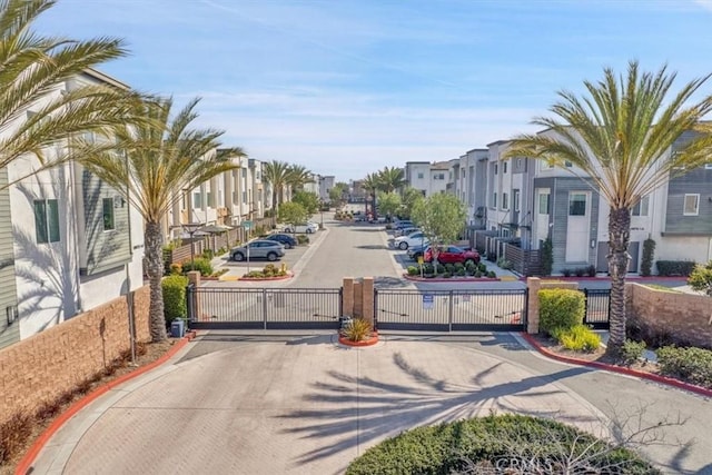 view of road with curbs, a residential view, a gated entry, and a gate