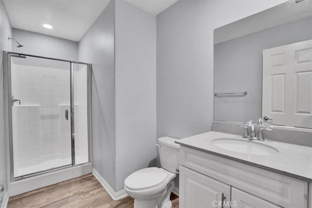 bathroom featuring a shower stall, baseboards, toilet, wood finished floors, and vanity