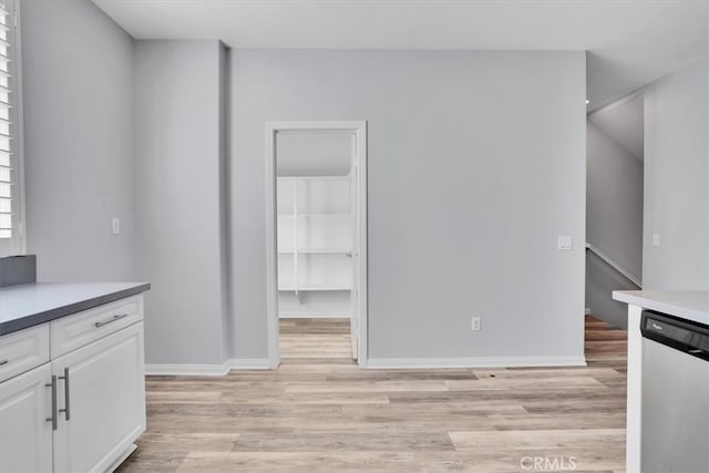 interior space featuring dishwasher, white cabinets, baseboards, and light wood-type flooring