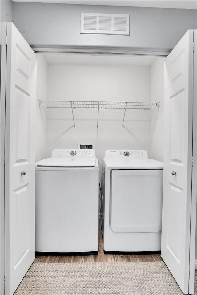 laundry area with washer and dryer, laundry area, wood finished floors, and visible vents