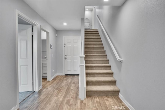 stairway with recessed lighting, baseboards, and wood finished floors