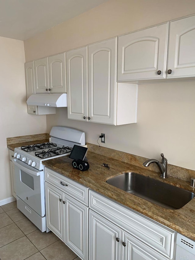 kitchen with white gas range, white cabinetry, under cabinet range hood, and a sink