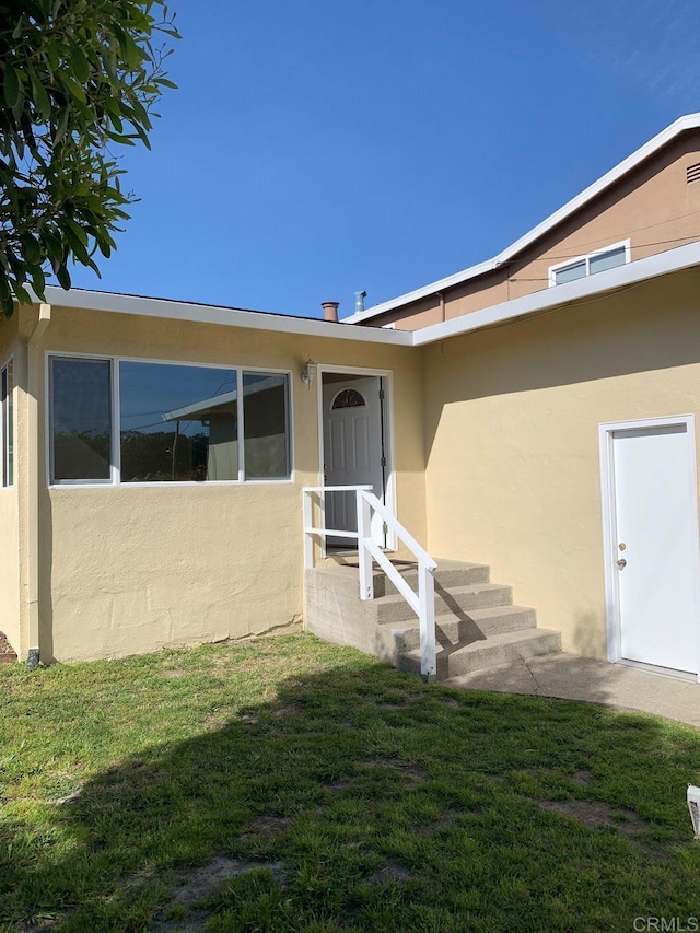 doorway to property featuring stucco siding and a yard