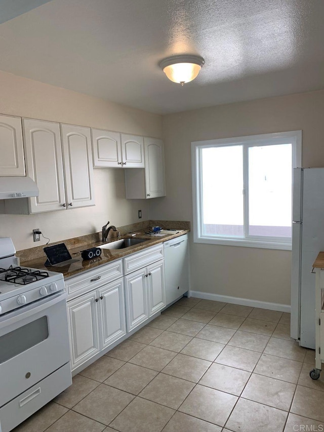 kitchen with under cabinet range hood, white appliances, white cabinets, and a sink