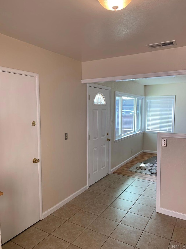 foyer with light tile patterned floors, baseboards, and visible vents