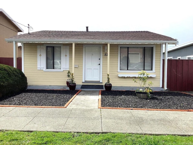 bungalow-style house featuring a shingled roof and fence