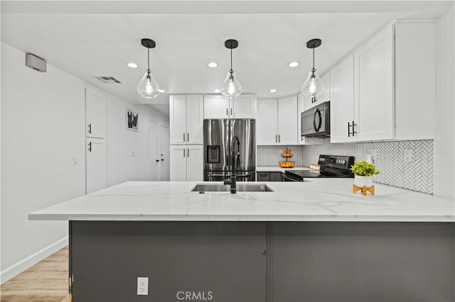 kitchen with black microwave, electric range oven, light stone counters, a peninsula, and stainless steel refrigerator with ice dispenser