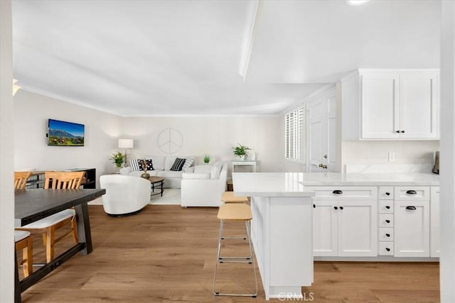 kitchen featuring a peninsula, white cabinets, light countertops, and light wood finished floors