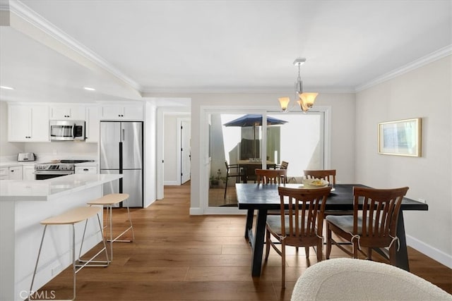 dining space featuring a chandelier, baseboards, wood finished floors, and ornamental molding