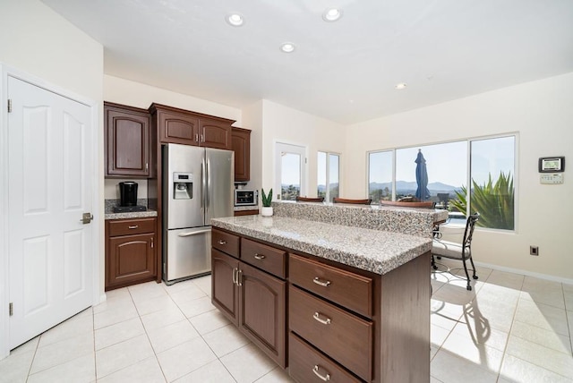 kitchen featuring light tile patterned floors, recessed lighting, dark brown cabinetry, stainless steel refrigerator with ice dispenser, and a center island