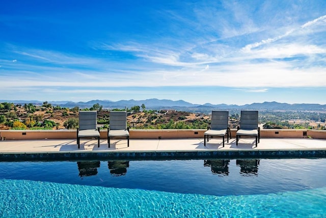 outdoor pool with a mountain view and a patio