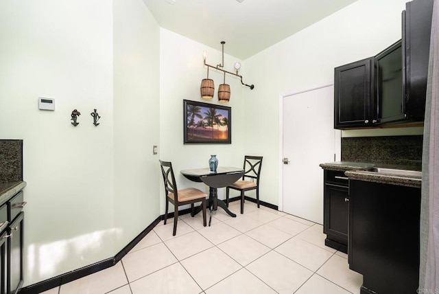 kitchen featuring dark countertops, light tile patterned floors, baseboards, and dark cabinets