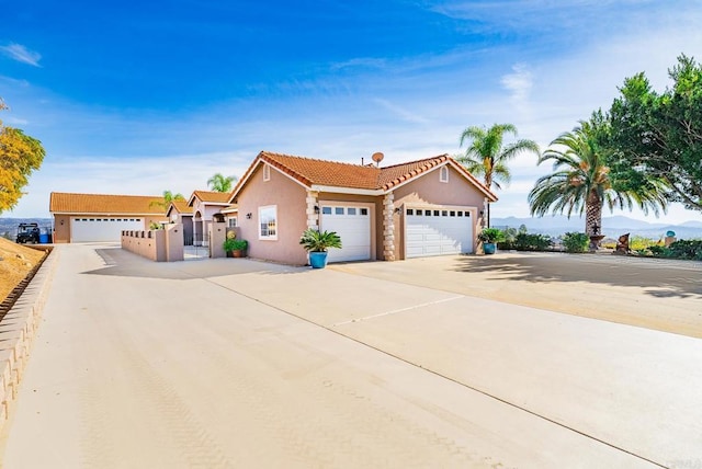 view of front facade featuring an attached garage, fence, a tile roof, stucco siding, and driveway