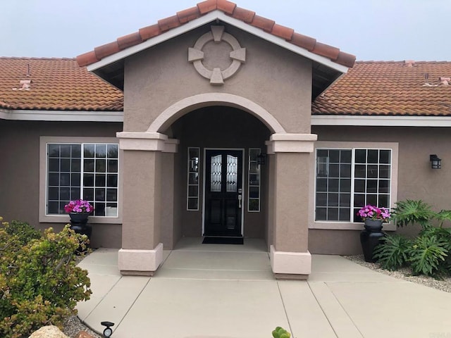 entrance to property featuring stucco siding and a tile roof