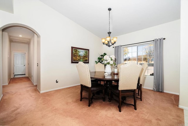 dining room featuring lofted ceiling, light colored carpet, arched walkways, and baseboards