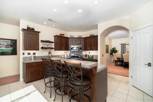 1185 Cedar Summit Dr, Ramona, CA 92065 - kitchen with appliances with stainless steel finishes, arched walkways, dark brown cabinetry, a center island, and a breakfast bar