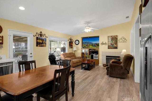 dining room featuring visible vents, light wood-type flooring, recessed lighting, a tile fireplace, and a ceiling fan