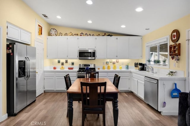 kitchen featuring light wood-style flooring, appliances with stainless steel finishes, light countertops, and a sink