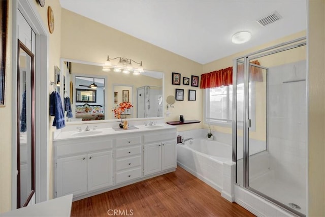 ensuite bathroom featuring a garden tub, a stall shower, visible vents, and a sink