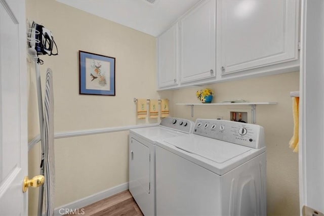 laundry area featuring washer and dryer, baseboards, cabinet space, and light wood-style flooring