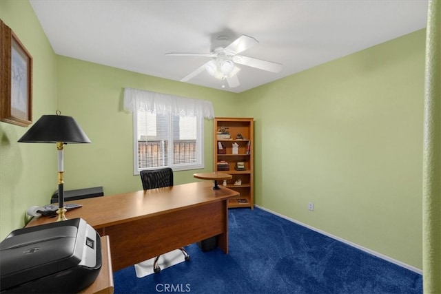 carpeted office space featuring baseboards and a ceiling fan