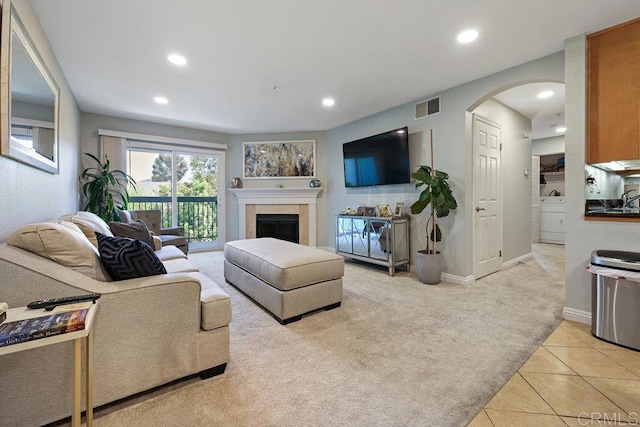 living room with visible vents, light colored carpet, recessed lighting, a fireplace, and arched walkways