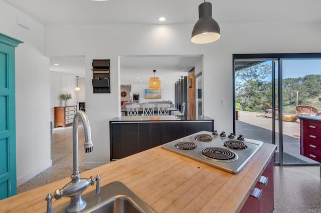 kitchen with pendant lighting, recessed lighting, stainless steel electric stovetop, speckled floor, and a sink