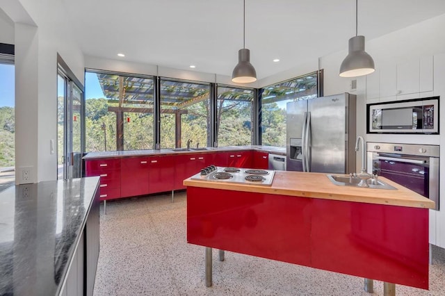 kitchen with a sink, light speckled floor, wooden counters, and stainless steel appliances