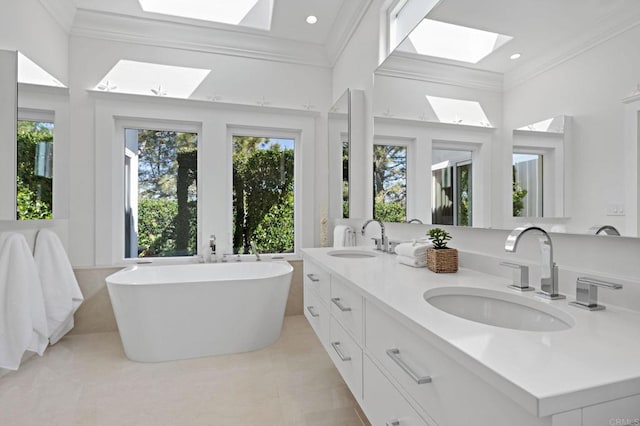 bathroom featuring a freestanding tub, a skylight, crown molding, and a sink