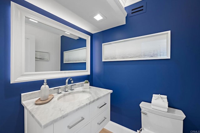 bathroom with toilet, vanity, and baseboards