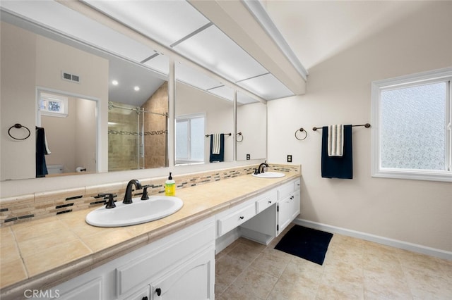 full bathroom featuring double vanity, a stall shower, lofted ceiling, and a sink