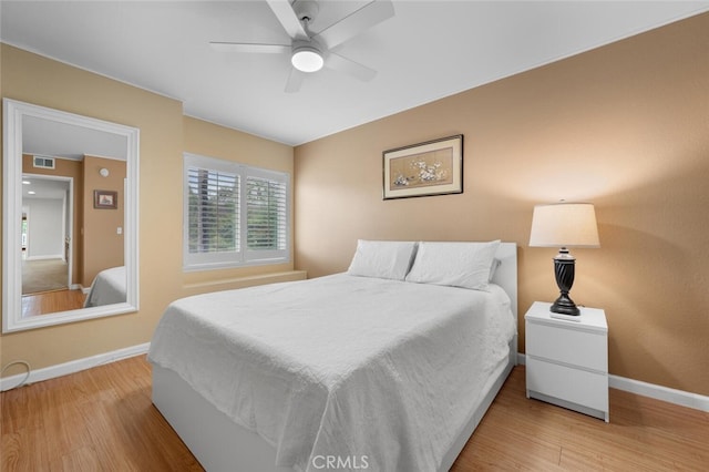 bedroom featuring visible vents, a ceiling fan, baseboards, and wood finished floors